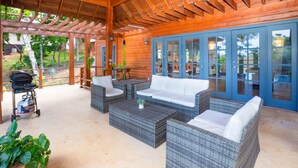 Un espacio al aire libre techado con mobiliario de mimbre y una parrilla.