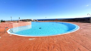 Una piscina circular con borde de azulejos, rodeada por un patio de ladrillo rojo.