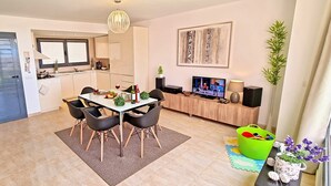 Una cocina moderna con comedor, televisor y zona de juegos verde.
