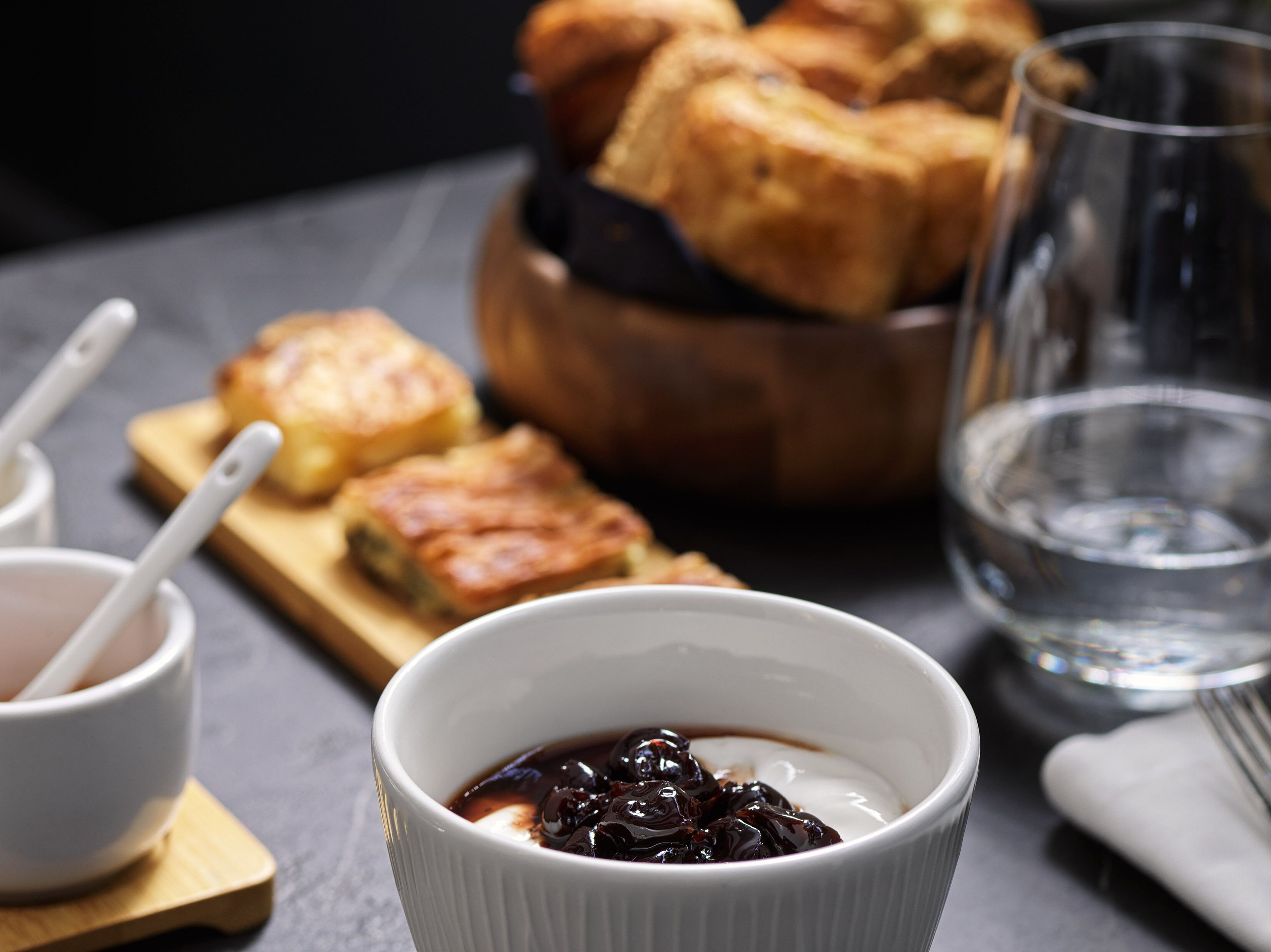 A dessert setting with a bowl of chocolate sauce and pastries on a wooden board.