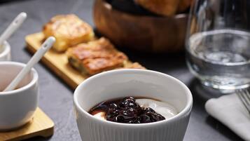 A dessert setting with a bowl of chocolate sauce and pastries on a wooden board.