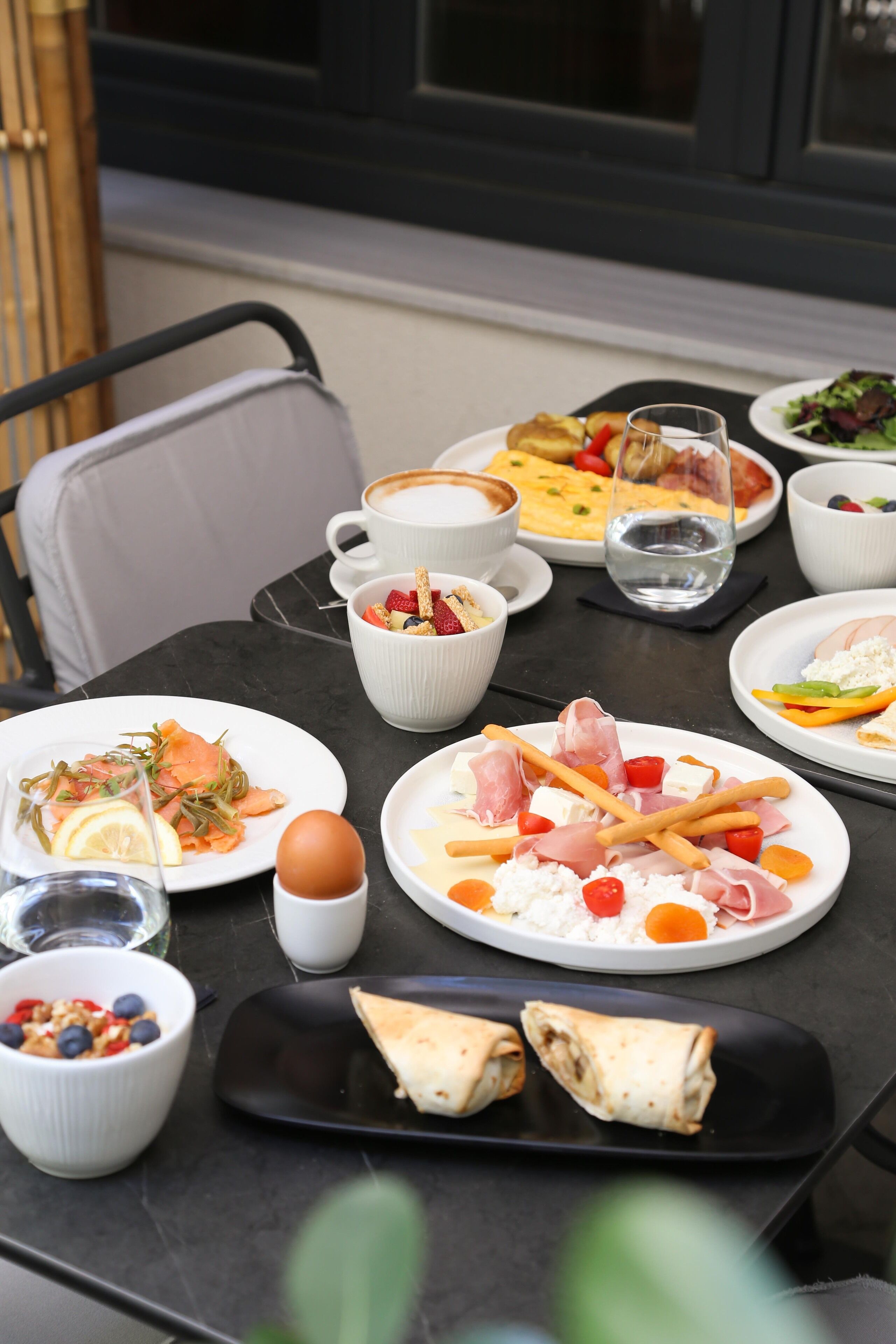 A table set with various dishes, including a plate of eggs, a bowl of salad, and a cup of coffee.