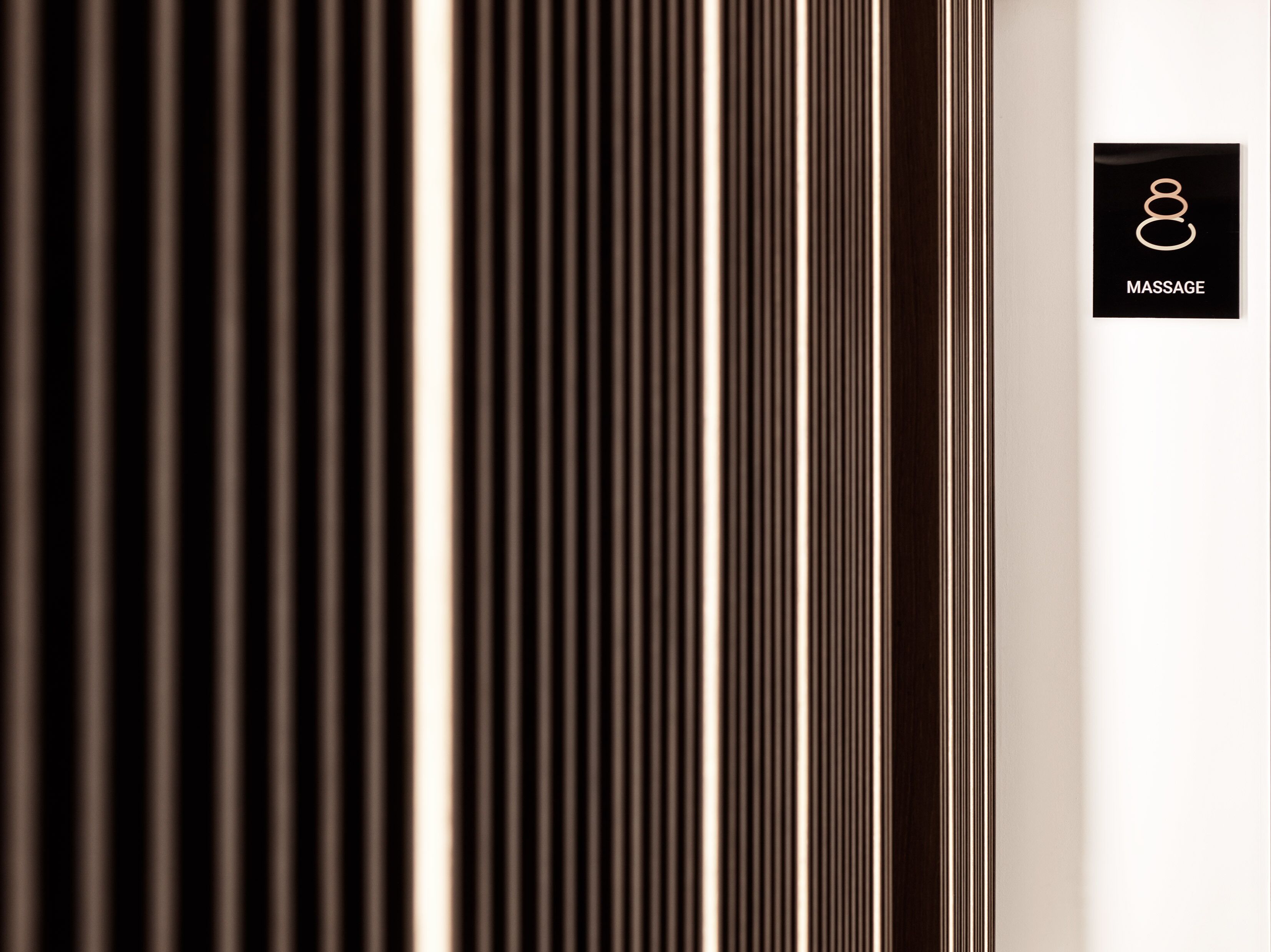 Paret amb llistons verticals de fusta i un cartell que indica servei de massatge.
