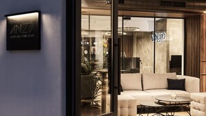 A modern lounge bar and restaurant with a glass partition, comfortable seating, and a visible clock. - Vanoro Hotel (Thessaloniki)