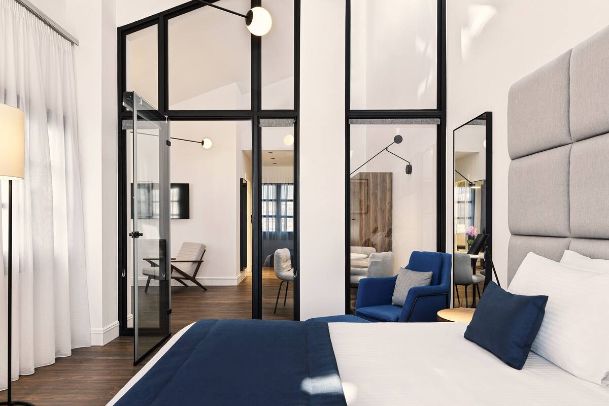 A modern hotel room with a large bed, a desk, and a chair.