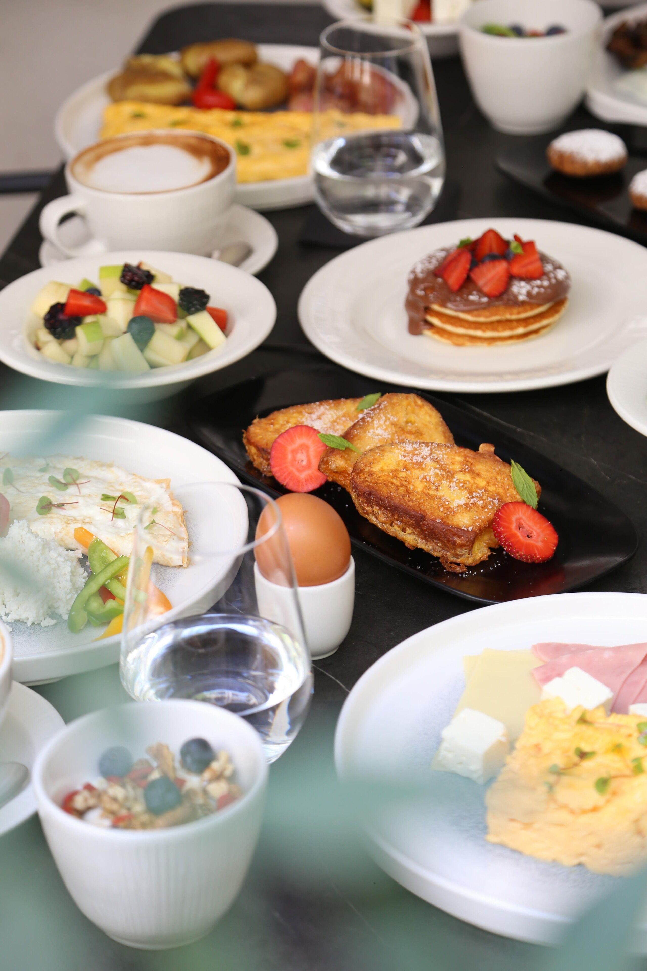 A variety of breakfast dishes on a table, including eggs, toast, fruit, and pastries.