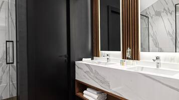 A modern bathroom with a dark door, a large mirror, and a marble countertop.