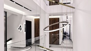 A modern interior with a glass railing, a wooden door, and a number '4' sign. - Vanoro Hotel (Thessaloniki)