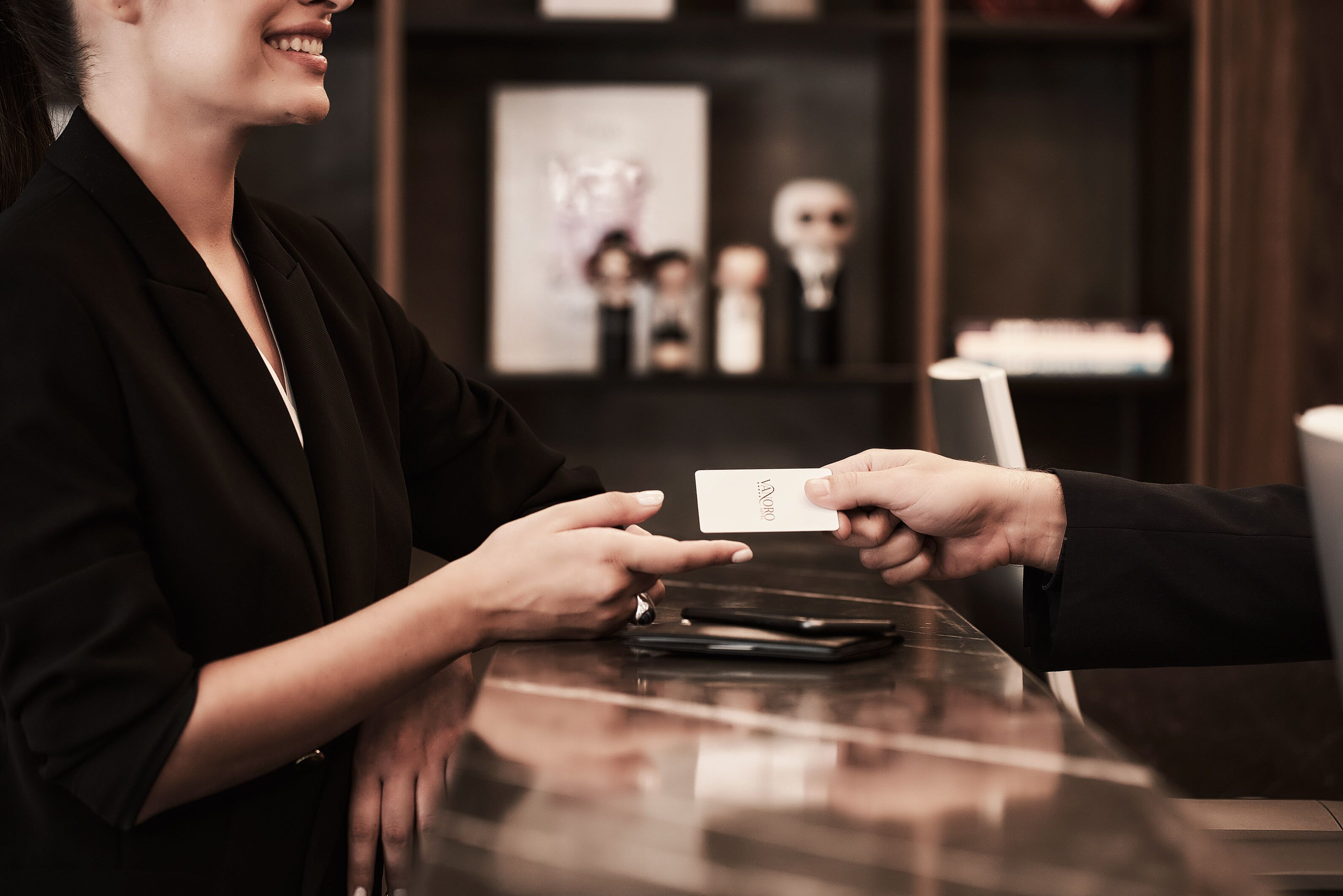 A person handing over a card to another at a counter.