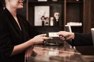 A person handing over a card to another at a counter.