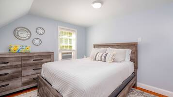 A bedroom with a wooden bed, a dresser, and a window with blinds.