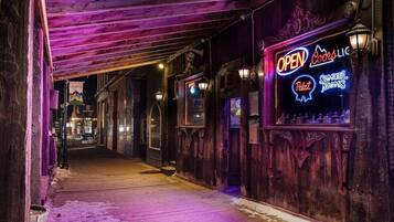 A narrow corridor with wooden walls and a neon sign indicating a bar named "OPEN Coors".