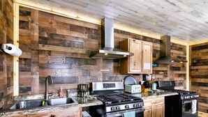 A rustic kitchen with wooden walls, a stainless steel stove, and wooden cabinets. - #10 Renovated Dog Friendly Cozy Room Leadville CO (Leadville)