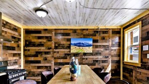A rustic wooden room with a long table, chairs, a stove, and a painting of mountains. - #10 Renovated Dog Friendly Cozy Room Leadville CO (Leadville)