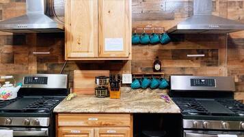 A kitchen with two gas stoves, wooden cabinets, a coffee station, and a stainless steel range hood.