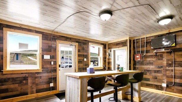 A room with wooden walls, a wooden ceiling, a desk with chairs, a television, and a window with a view of a building and landscape. - #10 Renovated Dog Friendly Cozy Room Leadville CO (Leadville)
