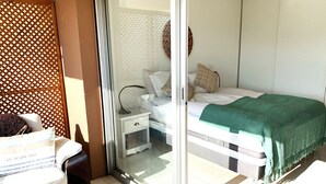 A bedroom with a bed, a nightstand, a chair, and a glass door leading to an outdoor area. - Lovely and bright apartment on the fifth floor with a large terrace. Garage! (Cannes)
