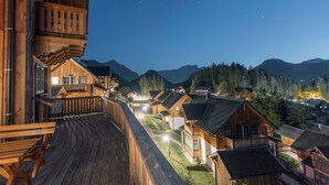 Una cabaña de madera con balcón, rodeada de otras cabañas y montañas.