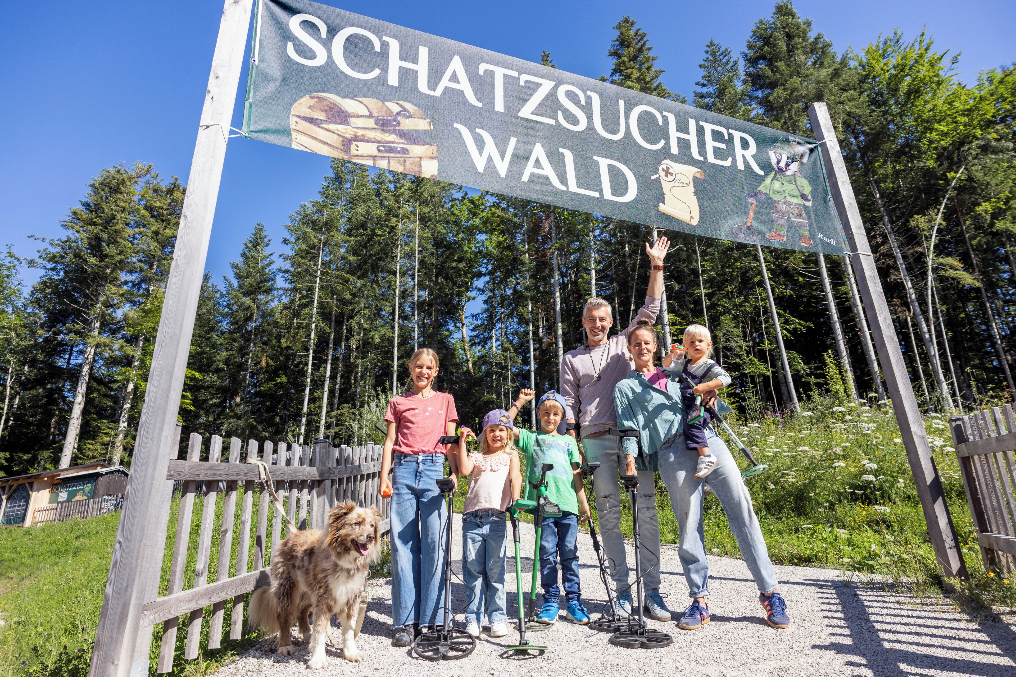A group of people standing in front of a sign that reads "SCHATZSUCHER WALD".