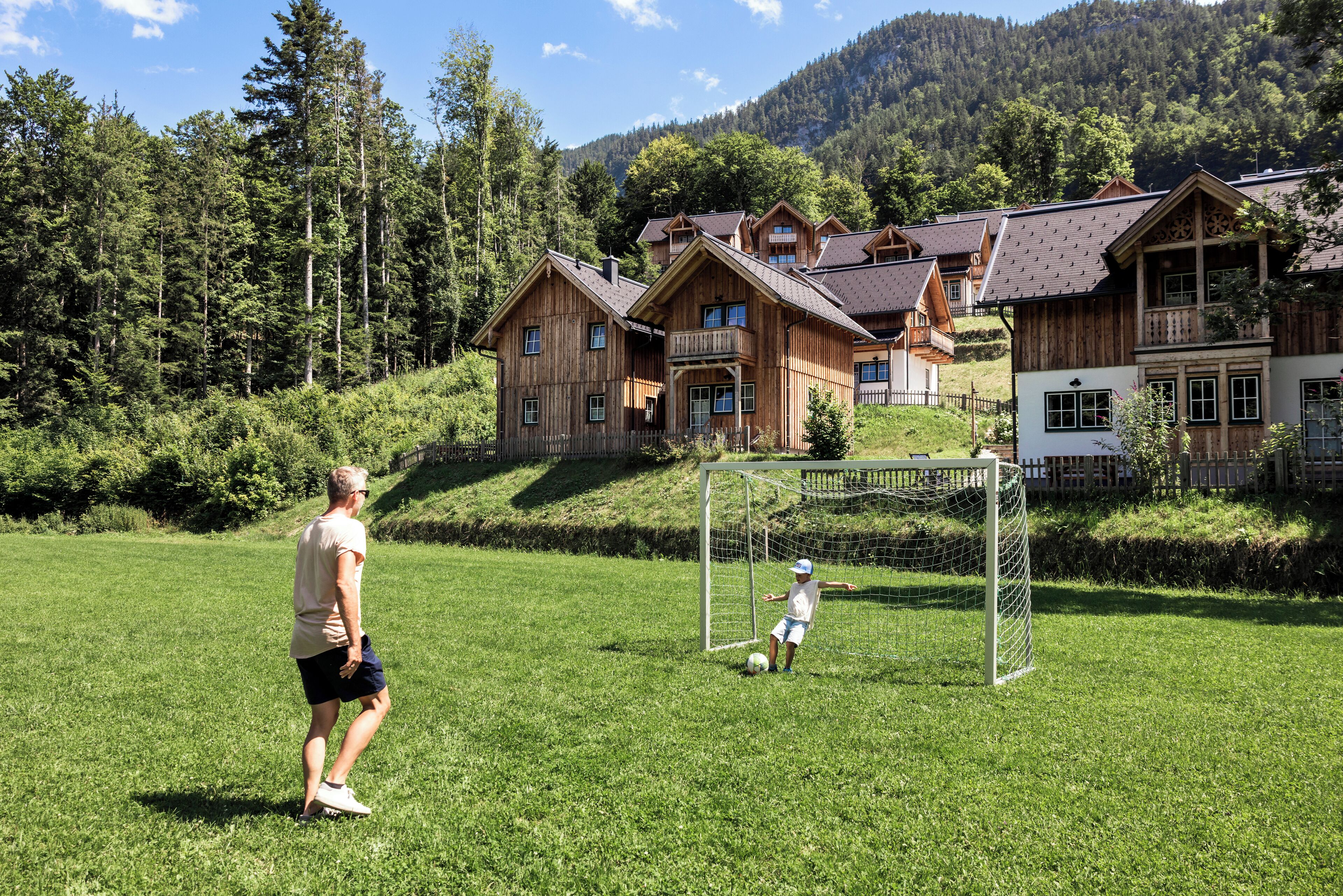 A man playing soccer on a grassy field with a goal in the background.