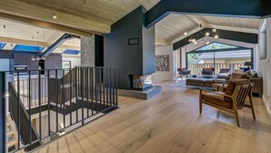 A spacious living area with a high ceiling, wooden beams, and a modern fireplace. - Chic & Spacious Chalet with Hot Tub & Sauna (Chamonix-Mont-Blanc)