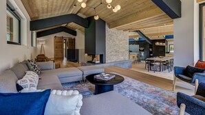 A spacious living area with a large sofa, a coffee table, and a dining area with chairs and a table. - Chic & Spacious Chalet with Hot Tub & Sauna (Chamonix-Mont-Blanc)