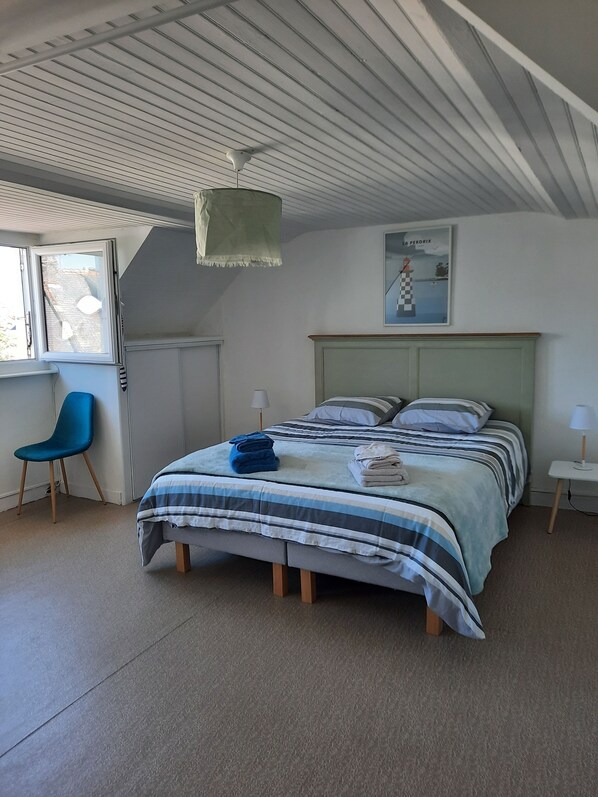 A bedroom with a bed, a chair, a lamp, and a painting on the wall. - 🌊 Ti Glaz - Île-Tudy – A charming home between the sea and the river (Île-Tudy)