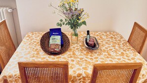 Ein Esstisch mit kariertem Tischlein, einer Vase mit Blumen, einer Flasche und einer Packung Motta Schokolade.
