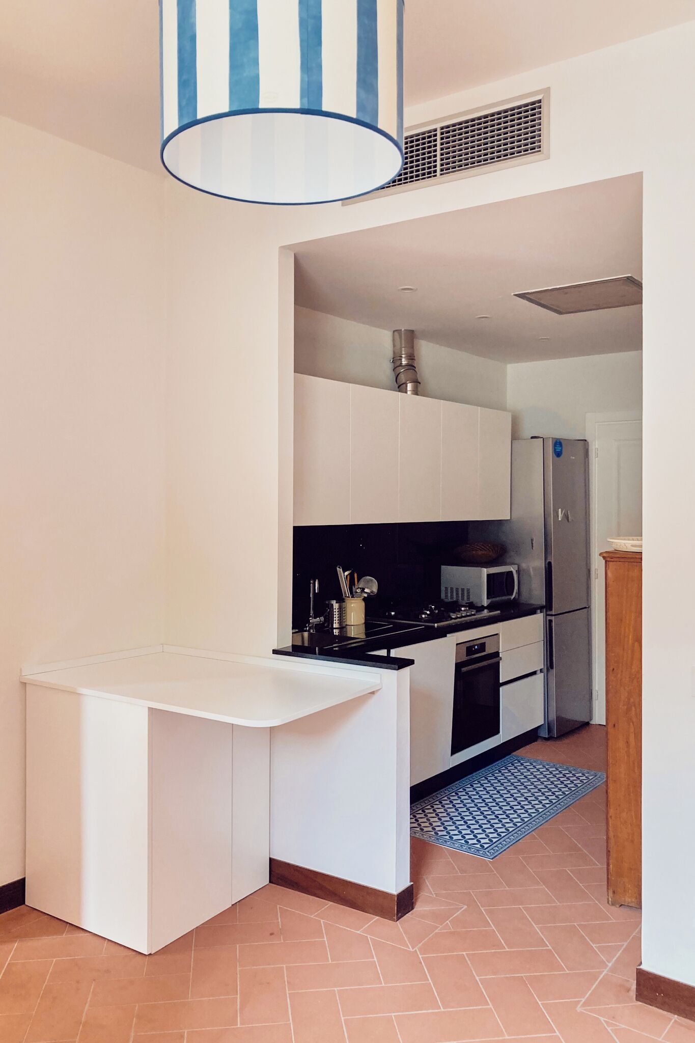 A modern kitchen with white cabinetry, a stainless steel refrigerator, and a microwave.