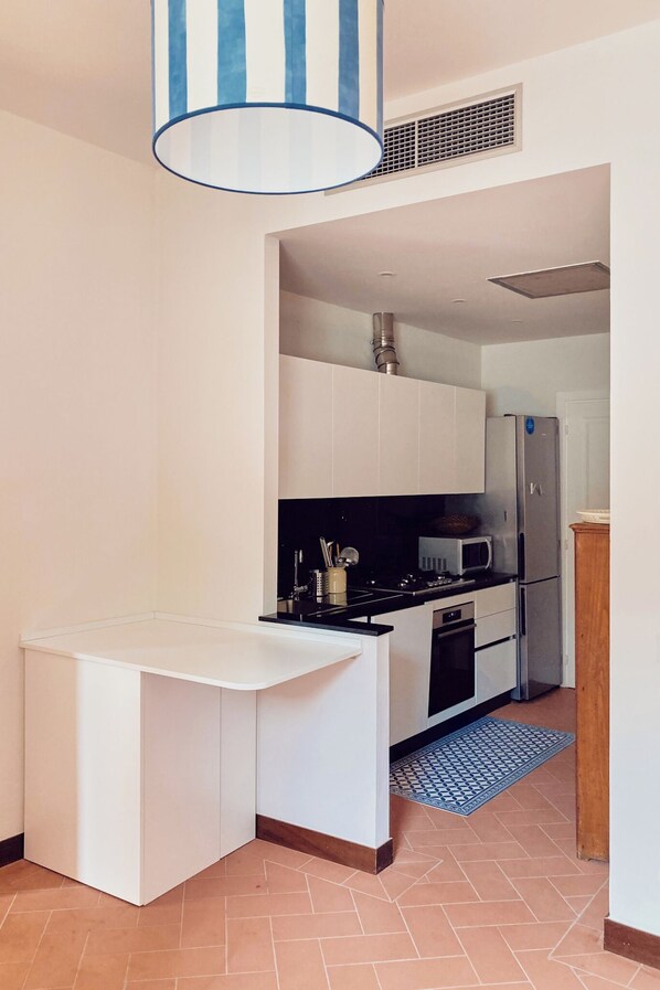 A modern kitchen with white cabinetry, a stainless steel refrigerator, and a microwave.