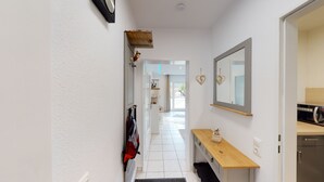 A hallway with a coat rack, a mirror, a wooden shelf, and a door leading to another room. - Vacation apartment in the Harz Mountains - Schulenberg (Schulenberg im Oberharz)