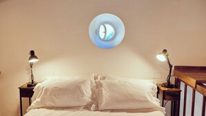 Ein Schlafzimmer mit einem Oberlicht, zwei Nachttischen mit Lampen und einem hölzernen Kopfteil.