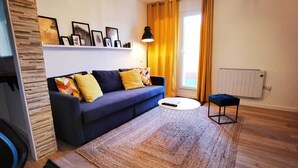 A living room with a blue sofa, yellow cushions, a round coffee table, and a patterned rug. - La Terraza de Alma (O Milladoiro)
