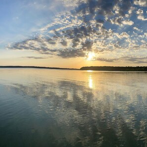 Un lac paisible, avec un coucher de soleil et des nuages se reflétant sur l’eau.