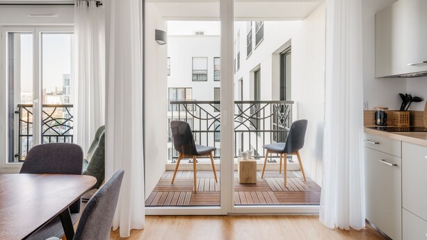 Un appartement moderne doté d’un coin repas, d’une cuisine et d’un balcon.