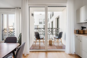 A modern apartment with a dining area, kitchen, and balcony. - Residence Edgar Suites Levallois - Jules Verne (Levallois-Perret)