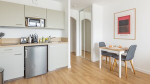 Une cuisine moderne équipée d’un four à micro-ondes encastré, d’un réfrigérateur et d’un coin repas avec une table et des chaises.