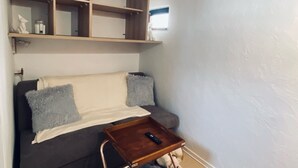 Ein gemütliches Wohnzimmer mit einem dunkelgrauen Sofa, einem Holztisch und einem flauschigen Teppich.