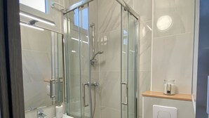 Ein modernes Badezimmer mit einer Duschkabine, einem weißen Waschbecken und einer Toilette.
