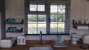 A kitchen with a sink, a toaster, a coffee maker, and a window with blinds. - Charming Luxurious Rural Shepherds Hut (Hook)