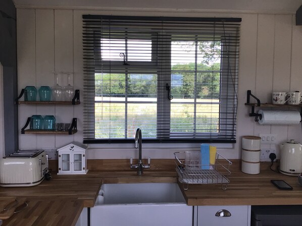 A kitchen with a sink, a toaster, a coffee maker, and a window with blinds. - Charming Luxurious Rural Shepherds Hut (Hook)