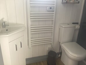 Un baño con lavamanos blanco, inodoro y barra para toallas.