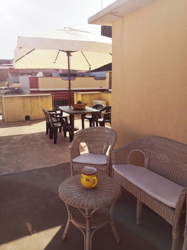 Relax on the patio with a wicker sofa, chair, and table, shaded by an umbrella.