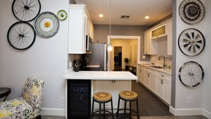 Una cocina moderna con armarios blancos, una isla central con taburetes y decoración con ruedas de bicicleta en la pared.