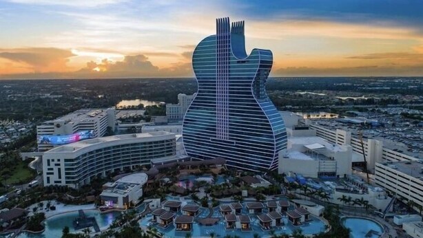 Ein modernes Hotel mit einem einzigartigen Design in Form einer Gitarre, mit mehreren Schwimmbecken und einer üppigen, grünen Umgebung.