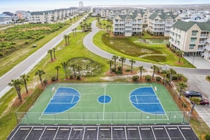 A residential area with a basketball court, a curved road, and apartment buildings.