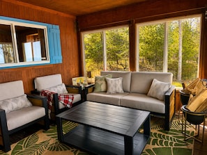 A cozy cabin interior with a sofa, chairs, a coffee table, and a fireplace.