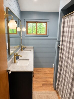 A bathroom with two sinks, a mirror, a window, and a shower curtain.