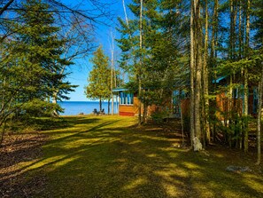 A cabin with a view of the lake, surrounded by trees.