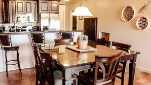 A modern kitchen with dark wood cabinets, a stainless steel refrigerator, and a central island with chairs. - Desert Willow Rim Vista 6A7 (Moab)